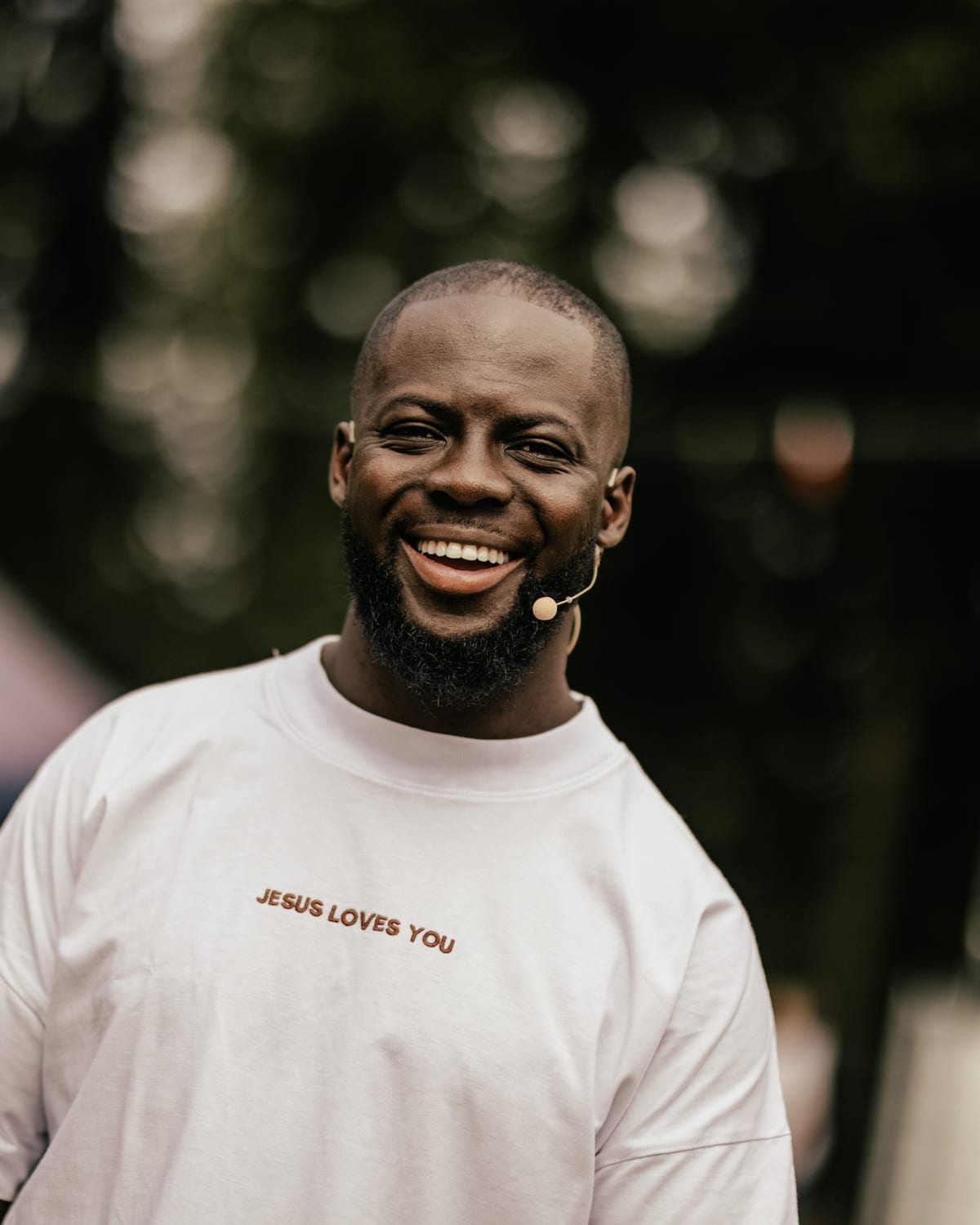 Godwin Arhin lacht met een headsetmicrofoon tijdens een spreekbeurt op een festivalterrein