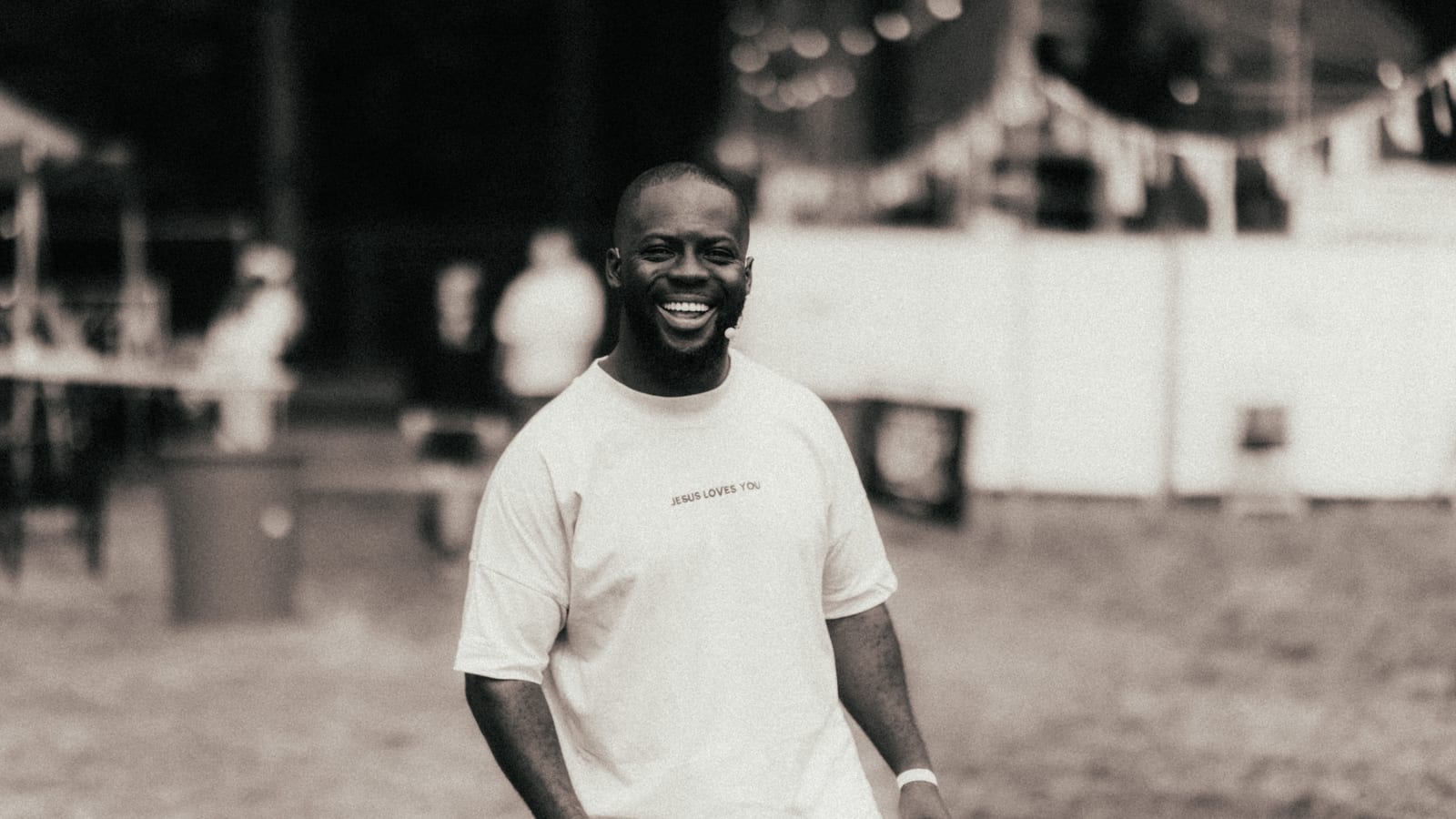 Godwin Arhin lacht met een headsetmicrofoon op een festivalterrein
